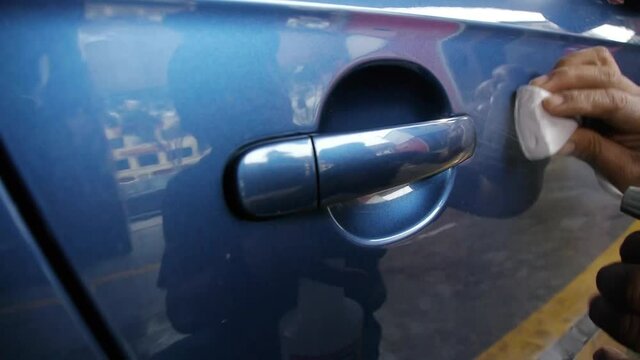 A man applying clay bar to the door and handle of a car