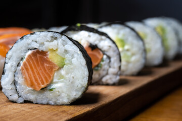 One set of Japanese salmon sushi rolls served on a wooden board.