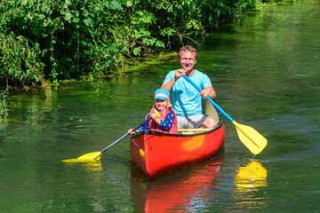 Vater und Tochter paddeln entspannt auf einem kleinen Fluss