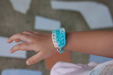 White and blue rubber band bracelet is woven for wearing a child's arm.