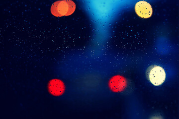 Obraz na płótnie Canvas Rain drops on car glass and colorful traffic bokeh light