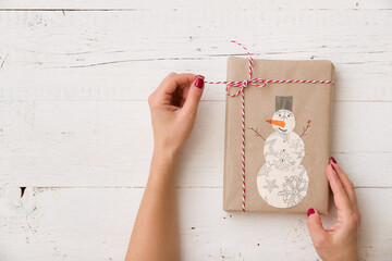Top view of a beautifully wrapped handmade gift. Girl holding a gift with a childish drawing of a...