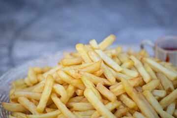 A plate of French fries is on the table. Food for the holiday and a quick bite in the fresh air. Junk food concept