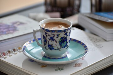 Turkish coffee in a traditional cup with ornament placed on a book