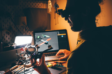 Man in virtual headset controlling FPV drone using laptop. Man building DIY quadcopter. 