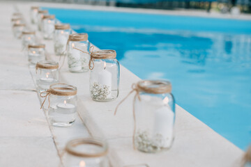 Gorgeous wedding decoration with candles inside crafted jars with water and Hypsophila flowers