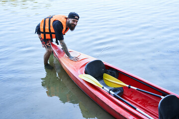 Obraz premium Man in safe jacket pulling canoe