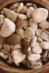 Close up decorative stones of different beige shades on a wooden plate. Top view