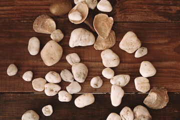 Close up decorative stones of different beige white gold shades on a blurred brown wooden table....