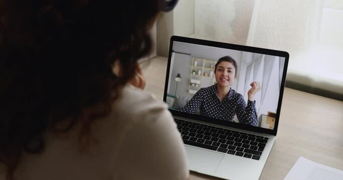 Indian ethnicity businesswoman talk by videoconference with colleague, laptop screen view over female shoulder. Easy method of negotiations, friendly personal communication, video call event concept