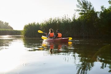 Side view of couple kayaking on river at evening