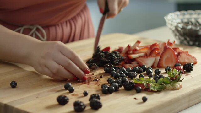 Woman slicing berries on a wood cutting board