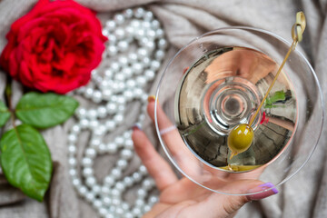 Young female caucasian hand holding a martini with olives, closeup, top view