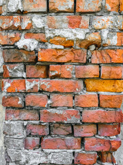 The texture of an old wall of red, orange uneven bricks with gray cement and concrete. Photography,...