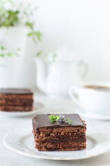 
A piece of chocolate cake with mint on white table