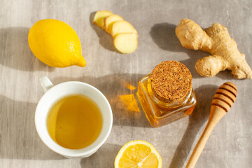 Hot drink with honey, lemon and ginger for cough remedy on gray table