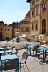 Medieval town Arezzo in Tuscany, Italy, main square (Piazza Grande), empty chairs and tables in front, a sunny day in autumn