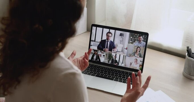 Businesspeople participate in group video call conference event, laptop screen view over female shoulder. Modern tech and distancing communication, negotiations by virtual meeting application concept
