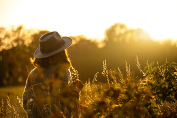 Silhouette of a woman dressed in a hat and with a backpack at sunset.