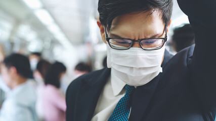 Young man wearing face mask travels on crowded subway train . Coronavirus disease or COVID 19...