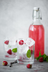 homemade raspberry lemonade in a bottle and glasses with ice