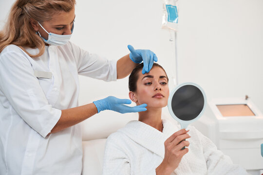 Woman Looking At Herself In The Mirror After Cosmetic Procedures