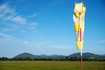 Yellow and white windsock placed in a large field during daylight