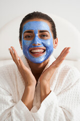 Woman with clay mask on surprised face