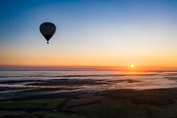 Travelling by hot air balloon, aerial landscape. Sun at dawn, horizon view. New day concept