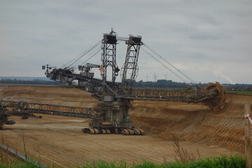 Fototapeta premium Schaufelradbagger in Braunkohle Tagebau Garzweiler. Fossile Energieträger in Deutschland. Schwere Werkzeugmaschine zur Kohleförderung und zum Erdreichabtrag. Lookout jackerath garzweiler skywalk.