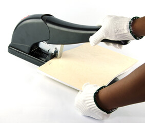 An employee is using a stapler for binding books with a lever that forces the paper to go up and...