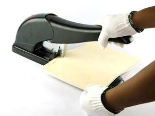 A person wearing white gloves was using a large mag to make a book.