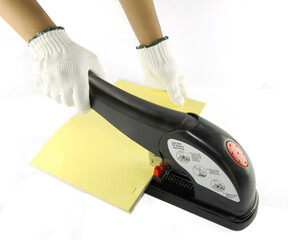 An employee is using a stapler for binding books with a lever that forces the paper to go up and...