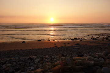 Obraz premium Malerischer romantischer Sonnenuntergang am Meer mit leichtem Wellengang. Treibgut an einem steinigen Strand. sligo strandhill ocean links connacht.