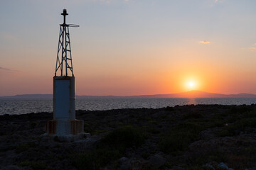 Fototapeta na wymiar Small lighthouse with sunset at the background at Agios Nikolaos village, Mani