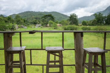 wooden table and chair for drink coffee and watching view of mountain farm landscape in sunlight.
