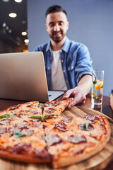 Close up Man with laptop in eating pizza at workplace