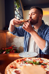 Man with beard eating tasty pizza