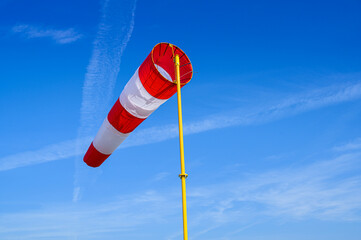 a striped meteorological windsock on a background of a blue sky