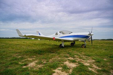 Fototapeta na wymiar a white-blue airplane on a green field of countryside airdrome