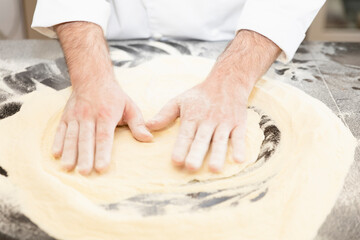 Obraz na płótnie Canvas Traditional Italian cuisine: chef prepares pizza dough with water and flour. food photography for menus and websites