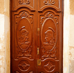 Puerta de madera de dos hojas con soldados romanos de perfil en Cáceres, Extremadura, España