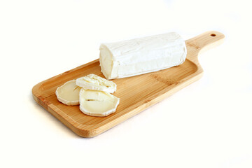 A tasty goat cheese roll atop a wooden cutting board over white background.