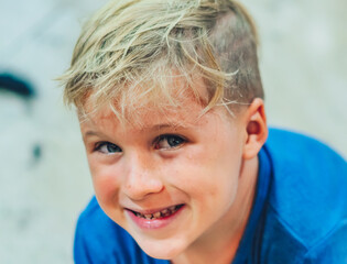 Close up portrait mischievous cute blond side looking blue eyed boy making freckles face play laughing in happy mood. Funny photo, happiness lifestyle. Daycare, simple joys happy childhood, behaviour