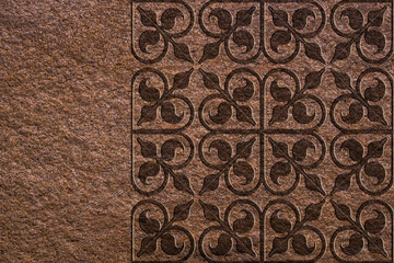 Ornamental print on a rough brown texture. Close-up of seamless texture. Texture wallpaper on the wall. Stone texture. Pattern on a stone surface