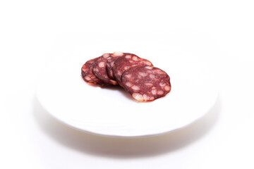 Sliced salami sausage jerky on a plate on white isolated background