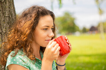 Young woman drinking tea at picnic and having a relaxing day