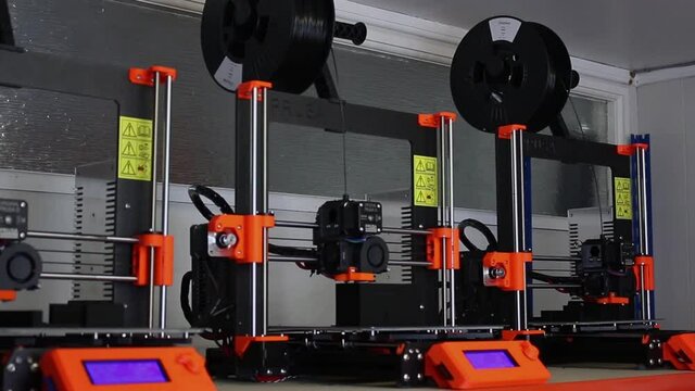 3 brand new Prusa I3 MK3 lined up on a shelf are all printing using black filament.