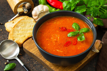 Vegan healthy food. Tomato soup or gazpacho on a dark stone or slate table.