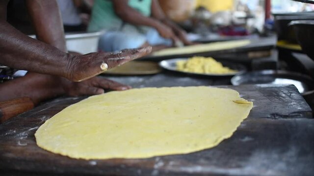 A man sprinkling flour on it and using rolling pin to flatten out the dough. Slow motion